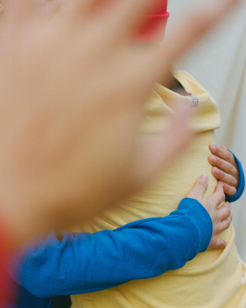 An image of two people embracing with a hand, out of focus, covering the scene from behind the camera.