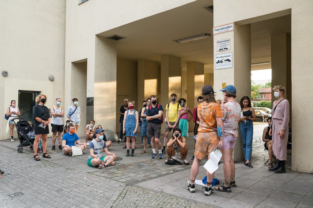 The audience sits with eyes closed in a building's entry way listening to Frances and Louise read a poem