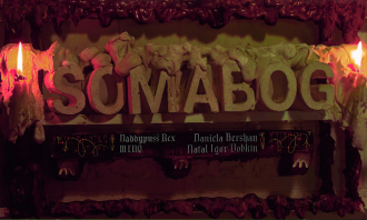 Letters made out of plaster spell out "somabog". Candles are lit next to them, with goopy foam in red and brown. The names Daniela Bershan, Daddypuss Rex, Miq, and Natal Igor Dobkin are written in old-looking script below.