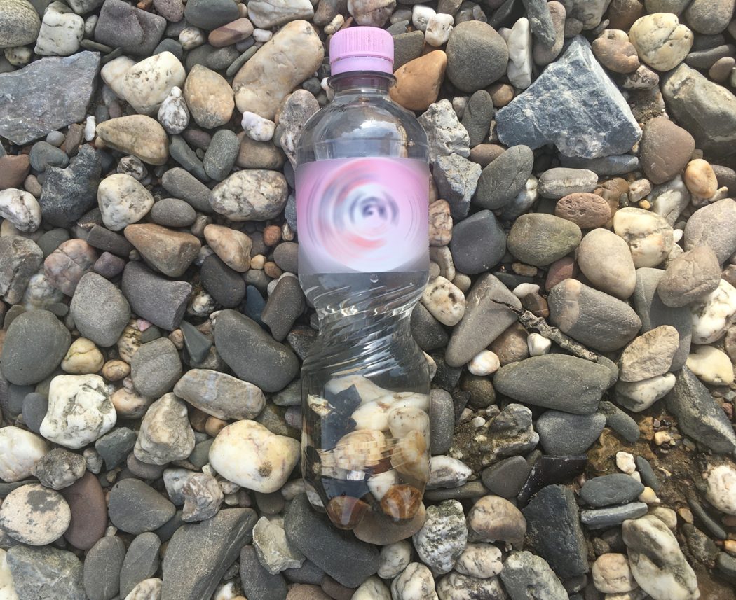 An image of a water bottle with a pink label and cap, resting on medium sized river rocks. The label text has been swirled in an obviously edited fashion.