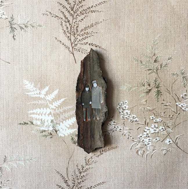 An image of a piece of tree bark on a beige piece of wallpaper with beige and white flowers. On the piece of bark is a black and white image of a couple which has been cut out around the outline.