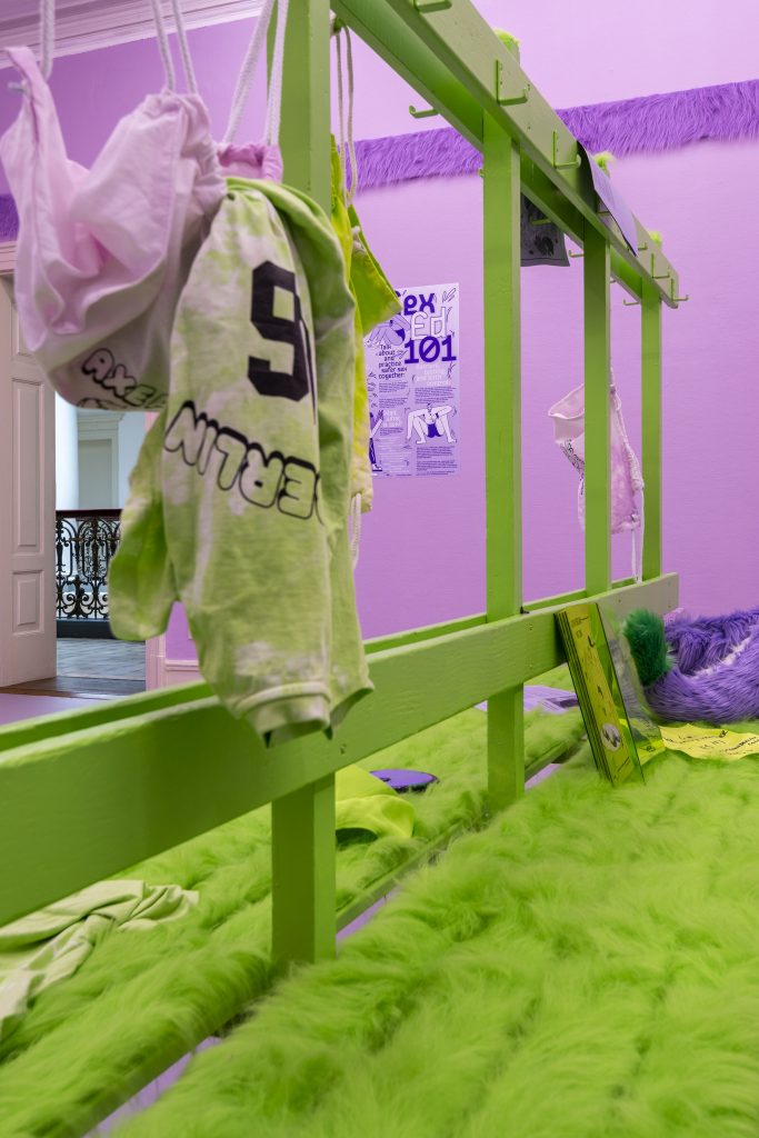 This is a close-up of the green fur from the changing room bench and clothes that have been sloppily flung about on the bench and from the hooks.